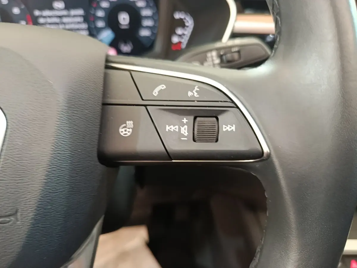 Gros plan sur les commandes gauche du volant cuir noir de l'Audi Q3 Sportback 2024 avec affichage numérique en arrière-plan.