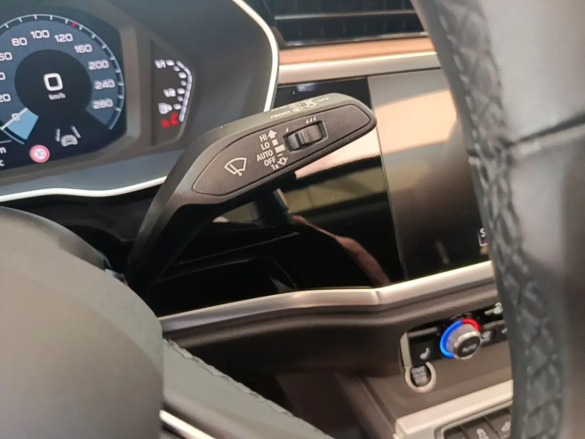 Gros plan sur la manette d’essuie-glace côté gauche du tableau de bord noir et écran tactile de l’Audi Q3 Sportback 2024.