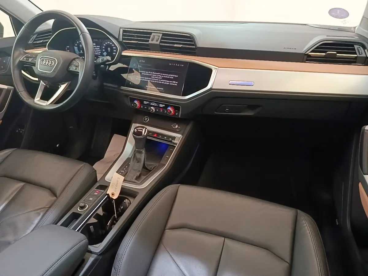 Intérieur de l'Audi Q3 Sportback 2024 vu côté conducteur, avec tableau de bord noir et inserts bois clair.