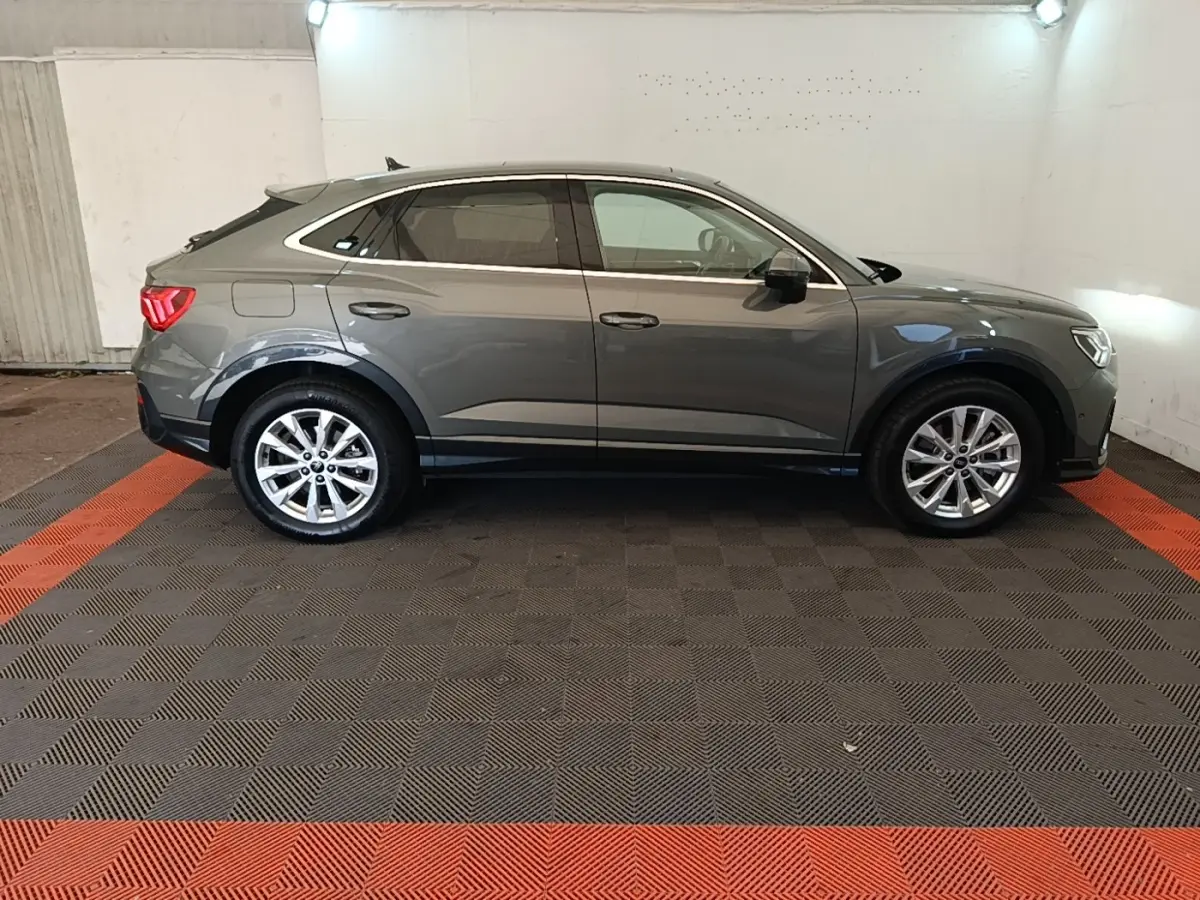 Audi Q3 Sportback gris vue de profil côté droit, avec toit incliné et jantes alliage visibles.