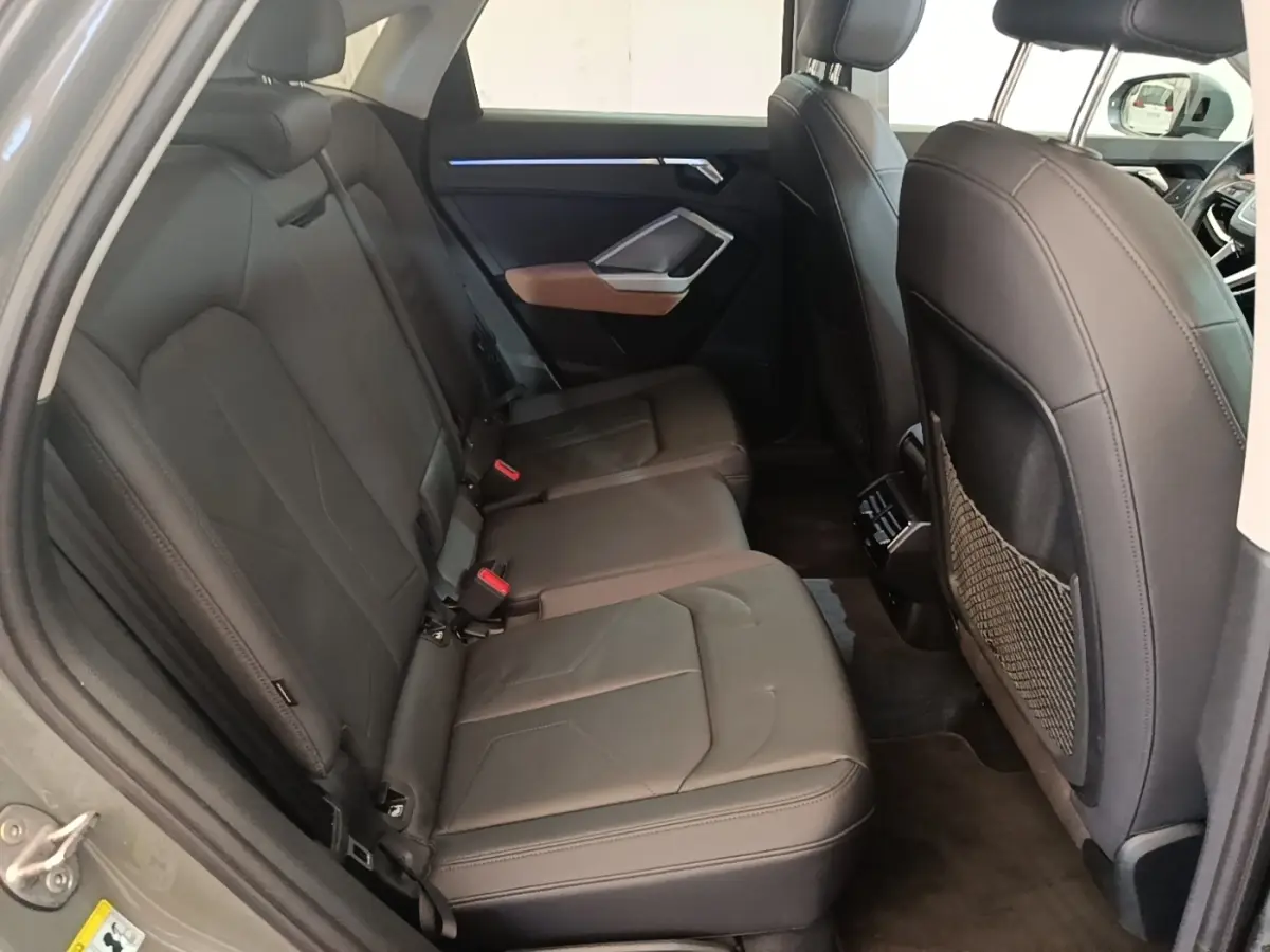 Vue latérale gauche de l'habitacle arrière de l'Audi Q3 Sportback 2024 avec sièges en cuir noir et détails marron sur la porte.