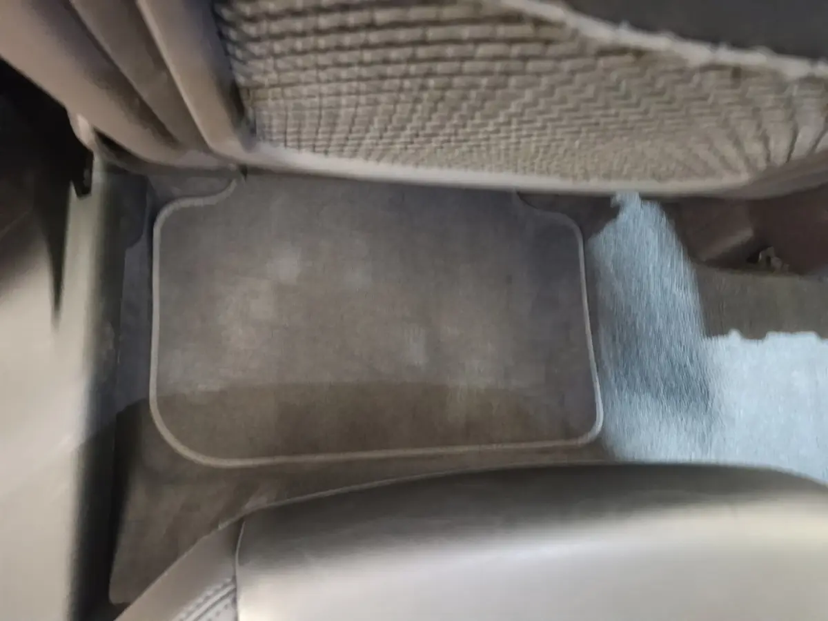 Vue rapprochée du tapis de sol arrière gris foncé et du dossier de siège en cuir noir dans un Audi Q3 Sportback 2024.