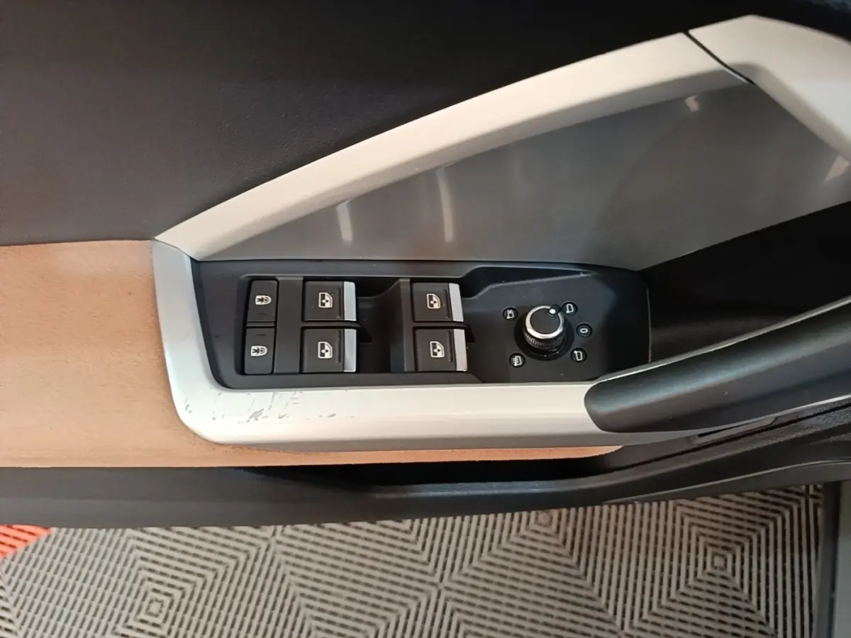 Gros plan sur la commande des vitres et rétroviseurs côté conducteur de l'Audi Q3 Sportback 2024 avec insert beige et noir.