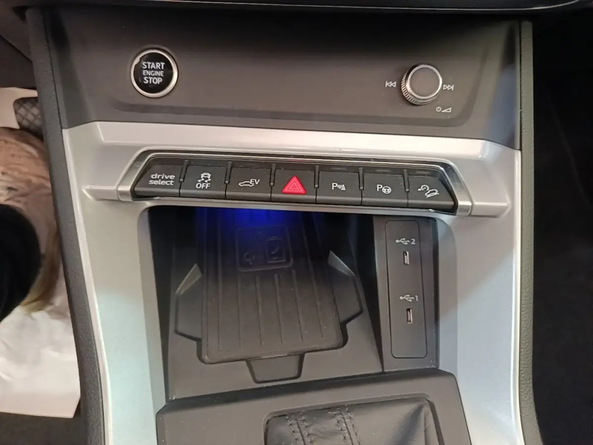 Vue rapprochée de la console centrale grise de l'Audi Q3 Sportback 2024 avec boutons de contrôle et ports USB visibles.