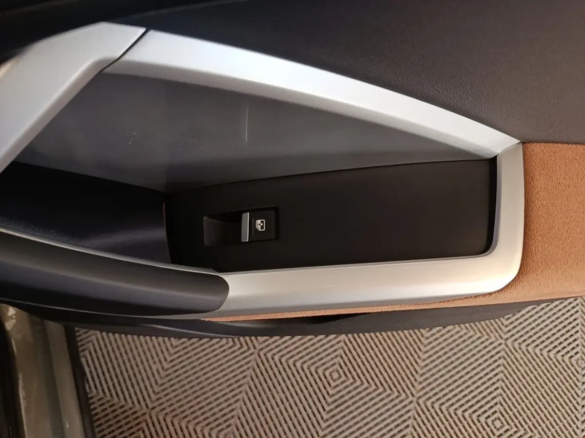 Détail de la commande de lève-vitre côté porte intérieure avec garniture marron et noire dans un Audi Q3 Sportback 2024.