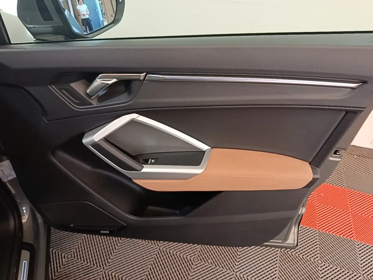 Vue latérale du panneau de porte avant gauche de l’Audi Q3 Sportback 2024 avec garniture noire et insert marron clair.