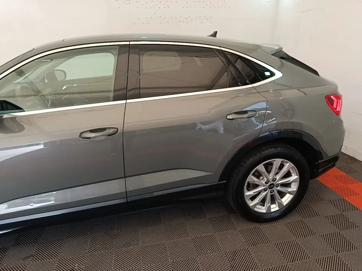 Vue latérale droite d'un Audi Q3 Sportback gris avec jantes alliage et vitres teintées.