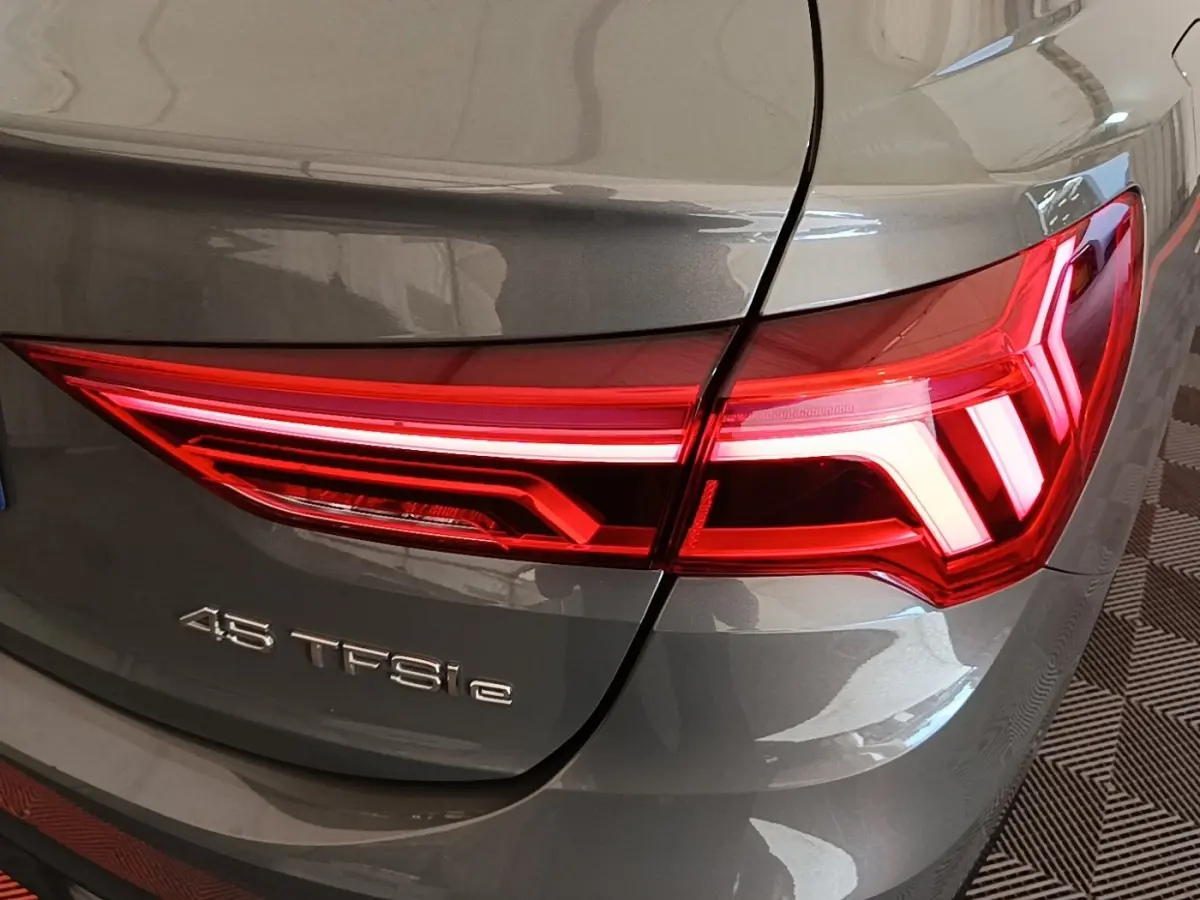 Gros plan sur le feu arrière droit rouge d’un Audi Q3 Sportback 45 TFSI e gris métallisé 2024.