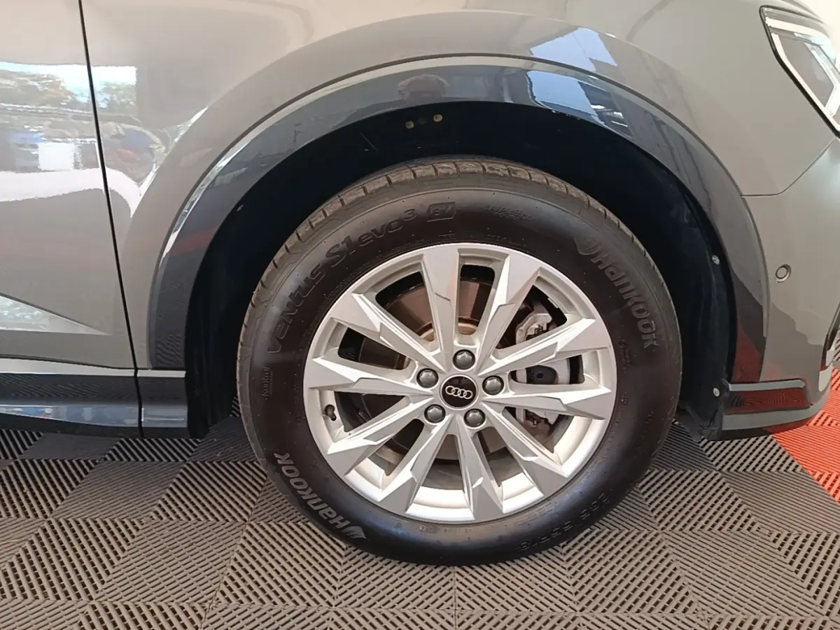 Gros plan sur la roue avant droite argentée d’un Audi Q3 Sportback 2024 gris avec jante à dix branches.