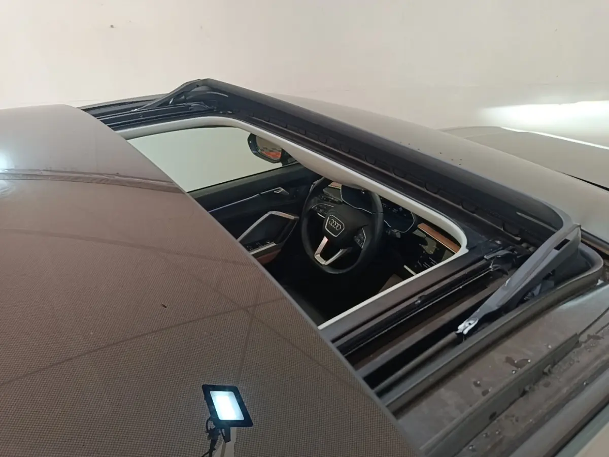 Vue plongeante sur l'intérieur noir d'un Audi Q3 Sportback 2024 avec toit ouvrant partiellement ouvert.