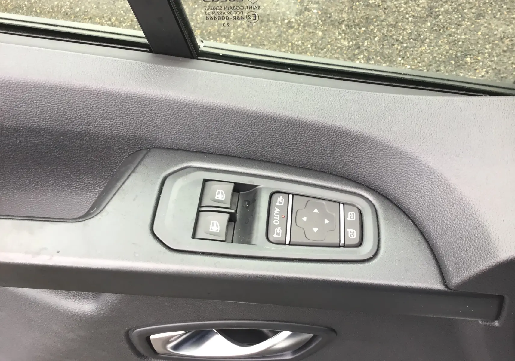 Commandes électriques des vitres et rétroviseurs sur la porte côté gauche du Renault Trafic Fourgon blanc 2023.