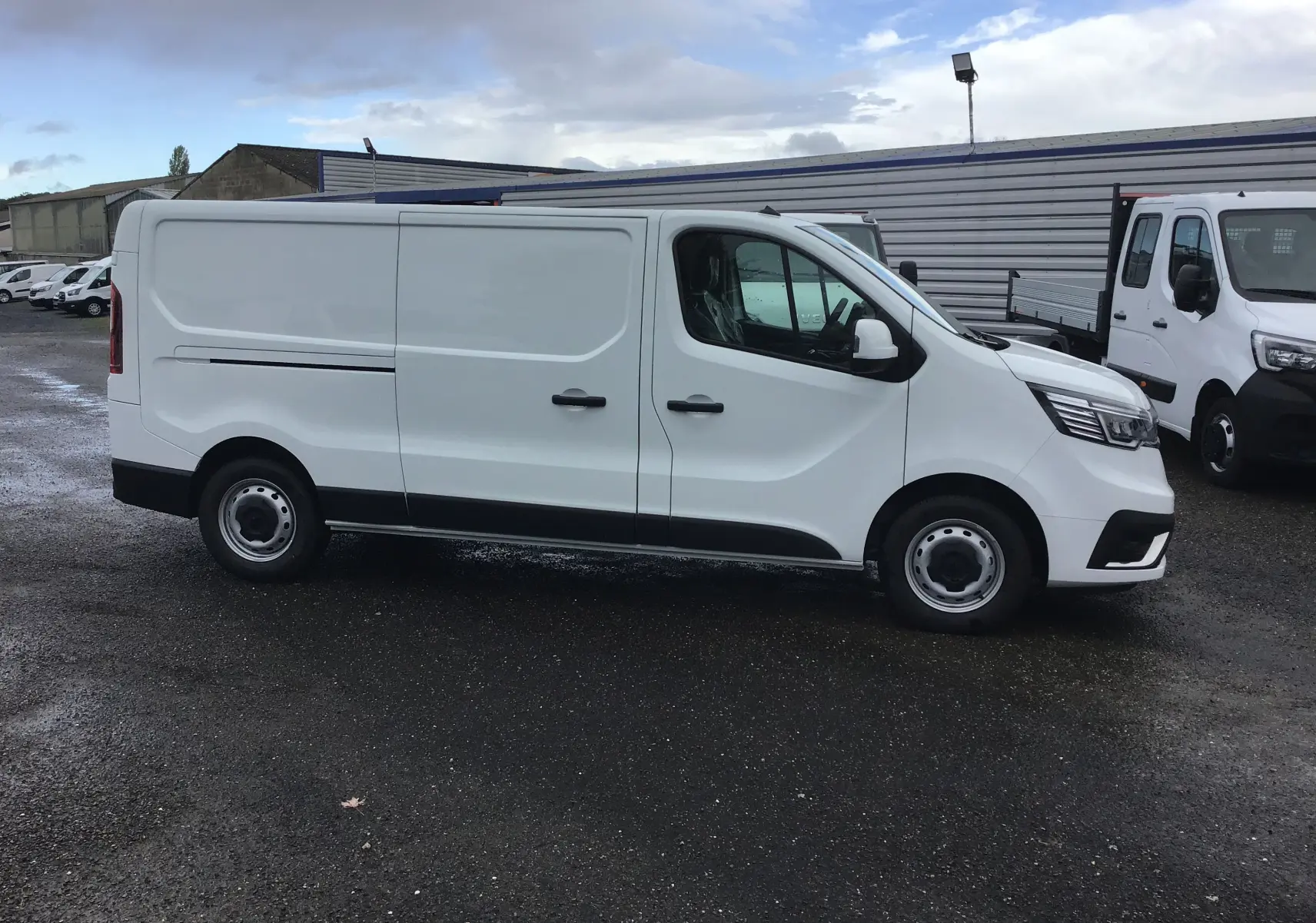 Renault Trafic Fourgon blanc en vue de profil côté gauche, avec portes coulissantes et jantes acier noires.
