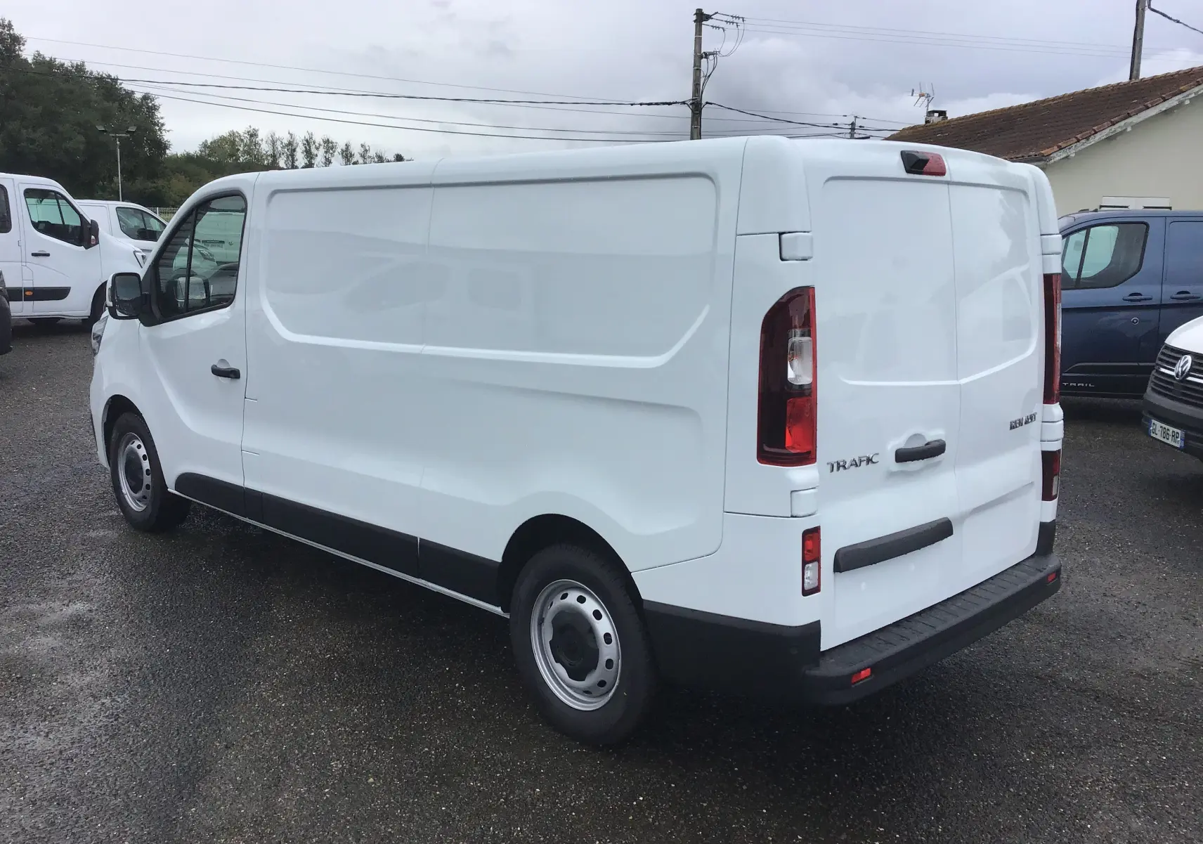 Renault Trafic Fourgon blanc en vue 3/4 arrière droit, avec portes arrière fermées et caméra de recul visible.