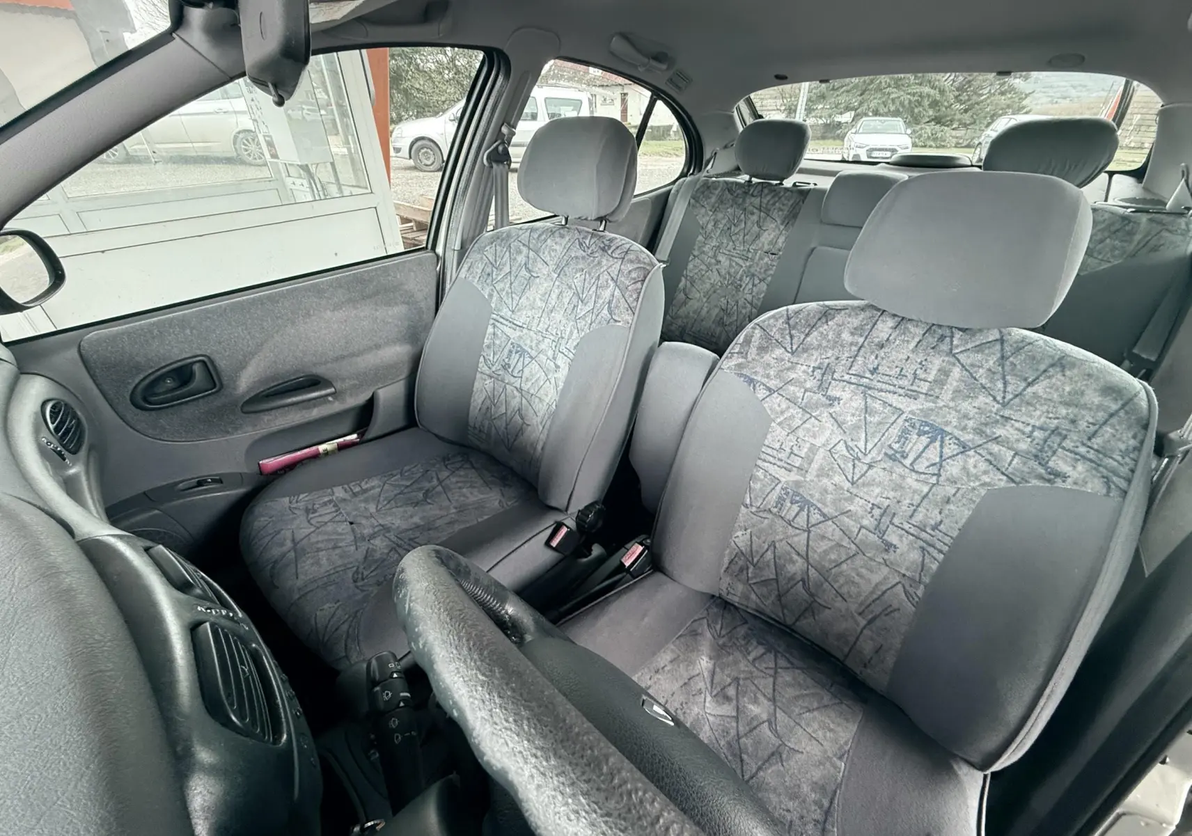 Vue intérieure avant droite de la Renault Mégane 1.6 i 110ch de 2000 avec sièges tissu gris à motifs géométriques.