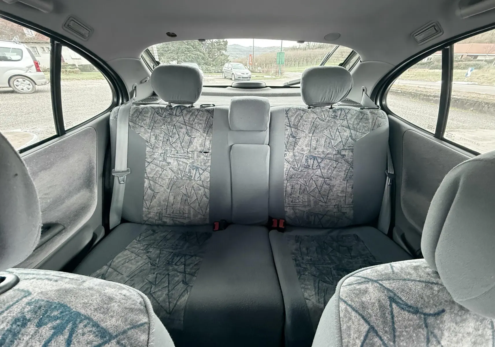 Vue intérieure arrière de la Renault Mégane 2000, sièges tissu gris avec motifs géométriques et appuie-têtes.