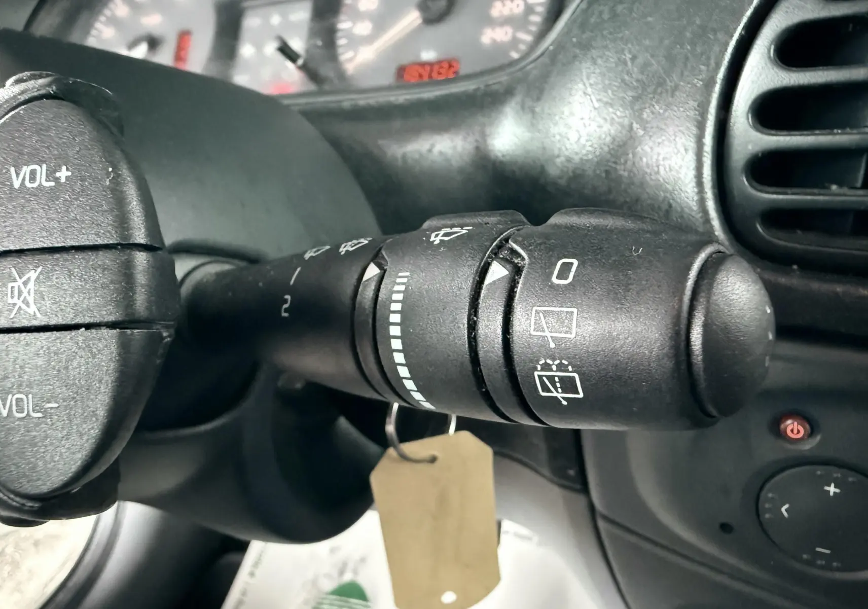 Gros plan sur la commande d'essuie-glace à droite du volant d'une Renault Mégane verte, tableau de bord en arrière-plan.