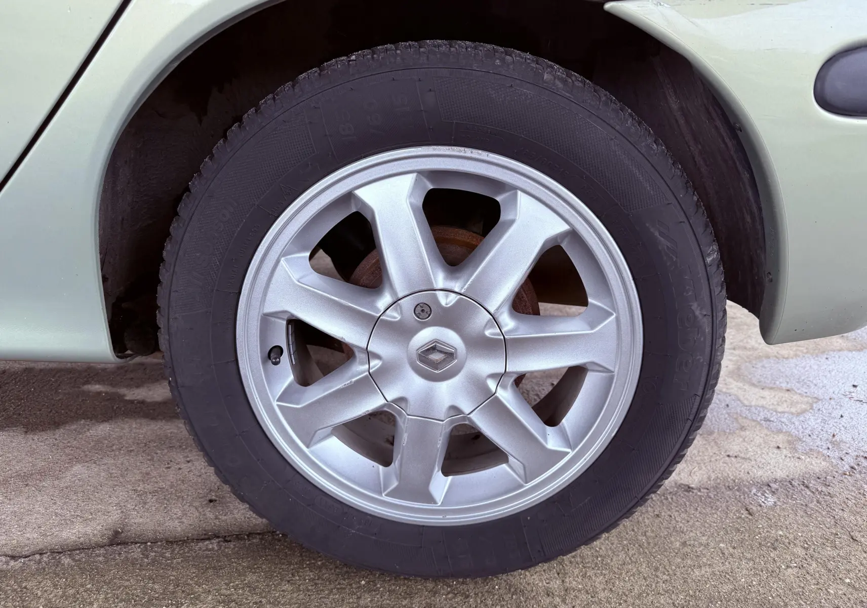 Gros plan sur la roue avant droite d’une Renault Mégane verte, avec jante alliage argentée et logo Renault central.