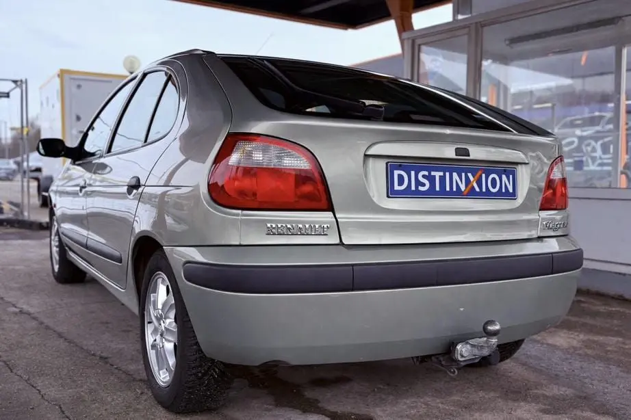 Vue 3/4 arrière droite d'une Renault Mégane argent avec attelage et hayon fermé sous abri.