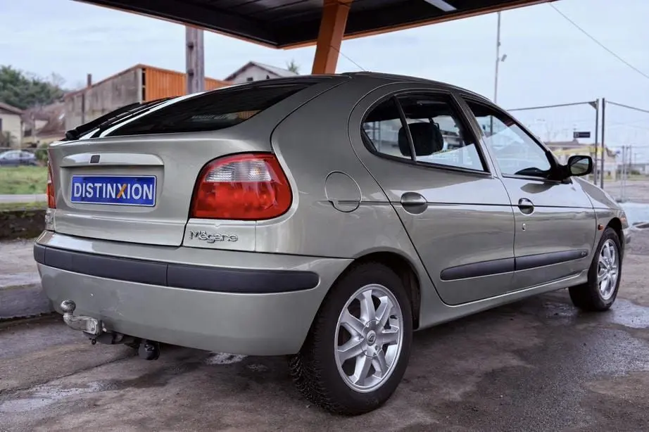 Vue 3/4 arrière droite d'une Renault Mégane gris clair cinq portes avec attelage et jantes alliage.