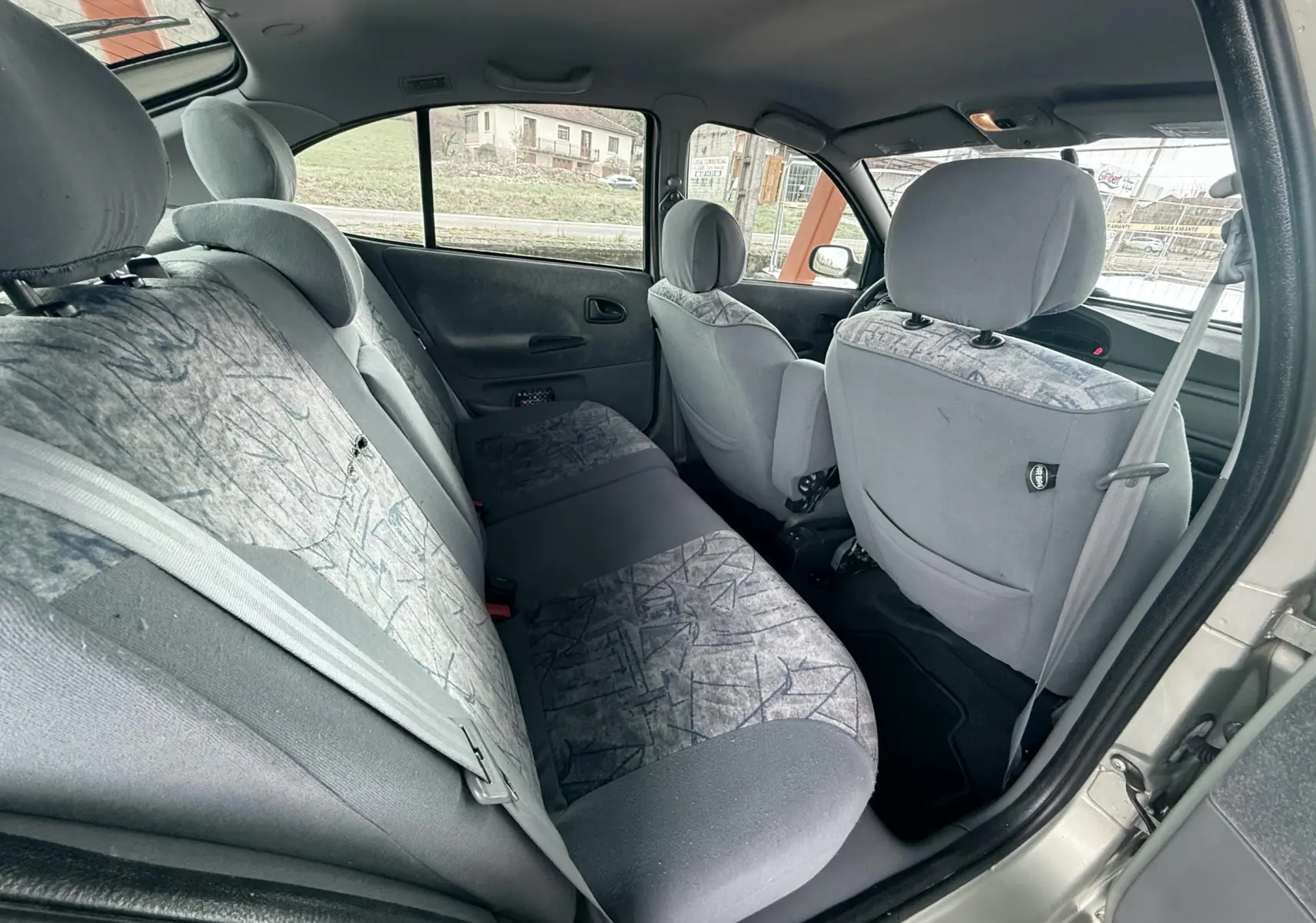 Vue intérieure arrière côté gauche montrant les sièges tissu gris avec motifs dans une Renault Mégane 2000.