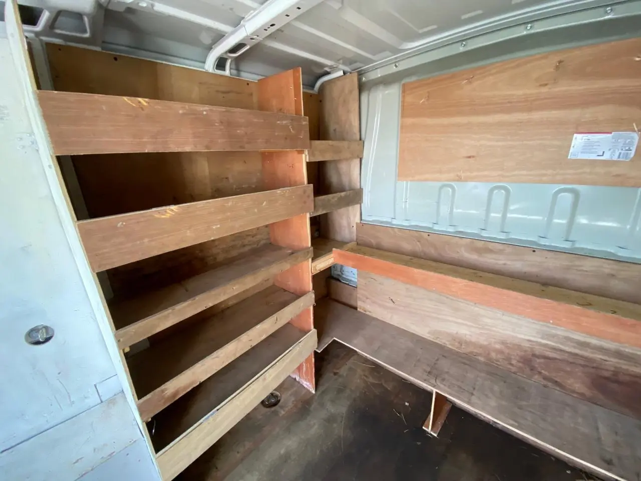 Intérieur du fourgon blanc Citroën Jumper 2013, vue en angle montrant les étagères en bois et le revêtement mural.