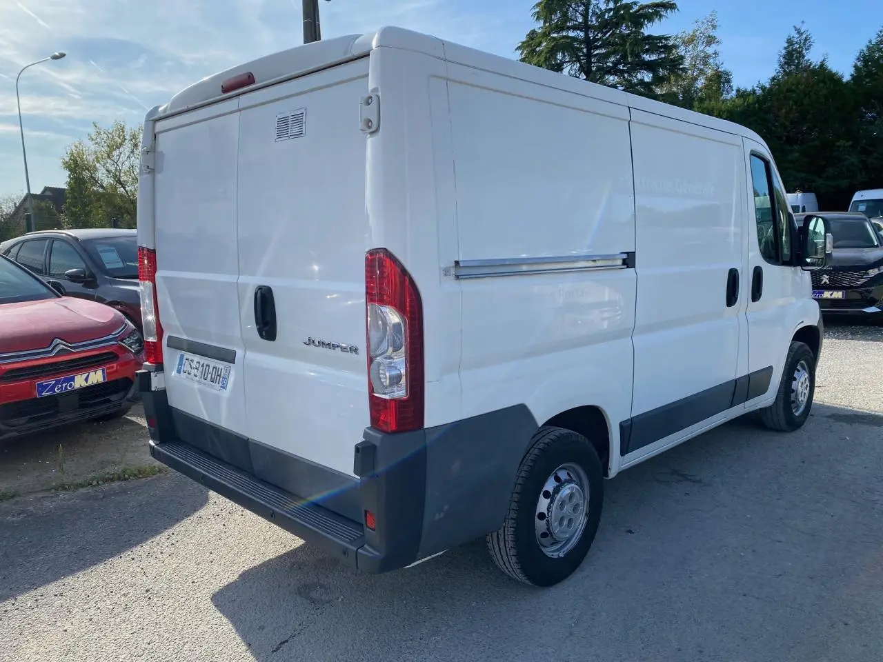 Vue 3/4 arrière droite d'un utilitaire blanc Citroën Jumper 2013 avec attelage et hayon arrière fermé.