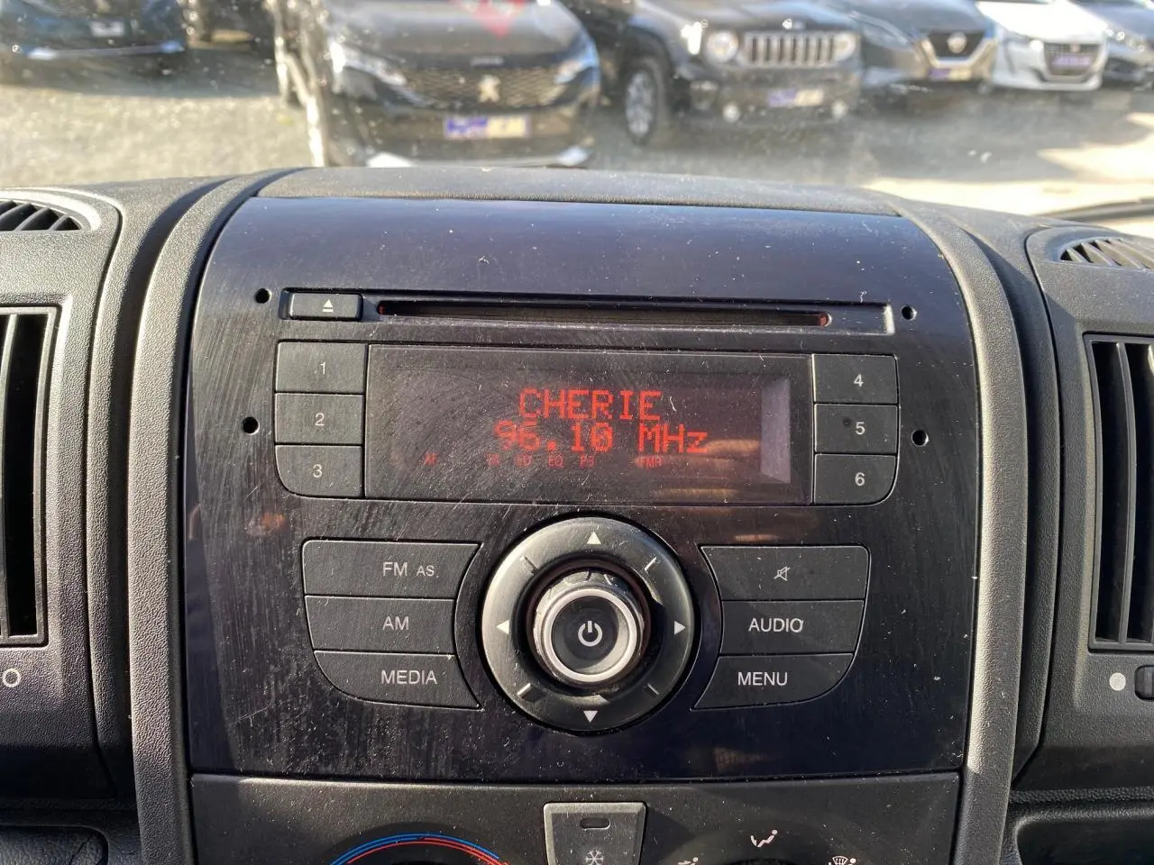 Vue rapprochée du tableau de bord noir du Citroën Jumper blanc 2013, affichant la radio sur 96.10 MHz avec station Chérie FM.