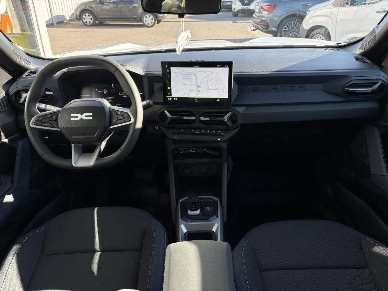 Vue intérieure avant du Dacia Duster 2024 avec tableau de bord digital et écran tactile central affichant une carte.