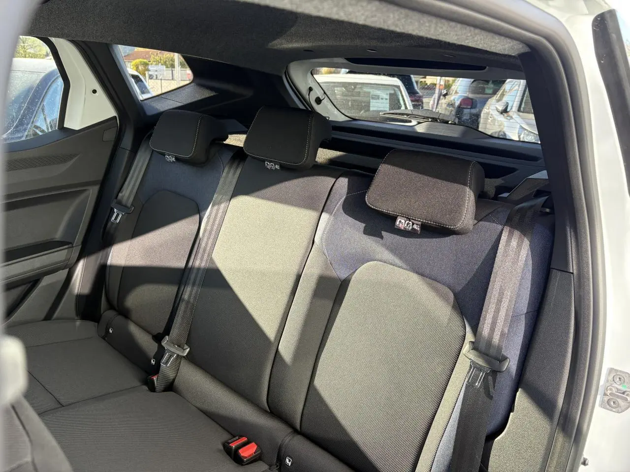 Vue intérieure de la banquette arrière noire du Dacia Duster blanc métallisé 2024 avec ceintures et appuie-têtes.