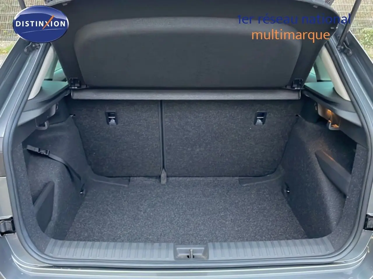 Coffre ouvert vu de l'arrière d'un Skoda Kamiq gris graphite métallisé, montrant un espace de chargement vide et propre.