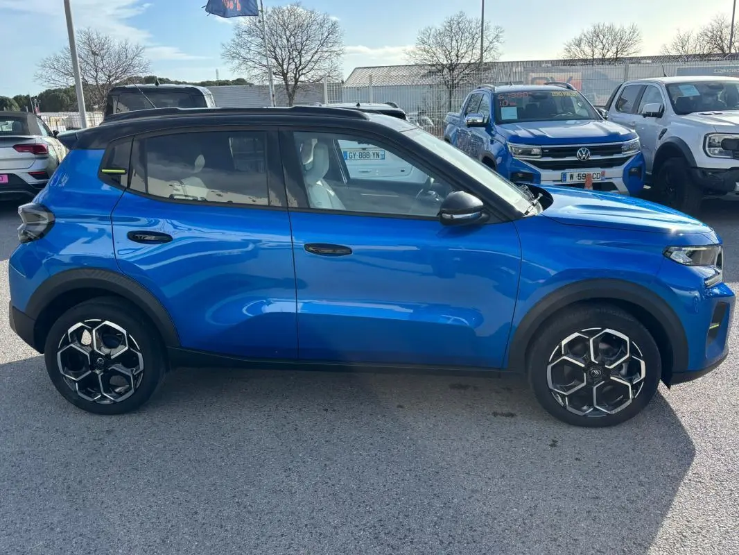 Vue latérale droite d'une Citroën C3 bleu 2025 avec jantes alliage noires et barres de toit visibles.