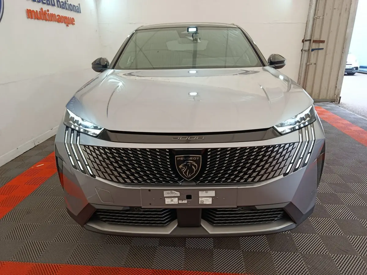 Vue avant frontale du Peugeot 3008 gris clair 2025 avec calandre distinctive et phares LED verticaux allumés.