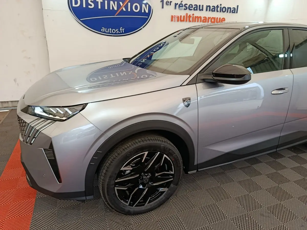 Vue de trois quarts avant gauche d’un Peugeot 3008 gris clair avec jantes noires et logo distinctif sur l’aile avant.