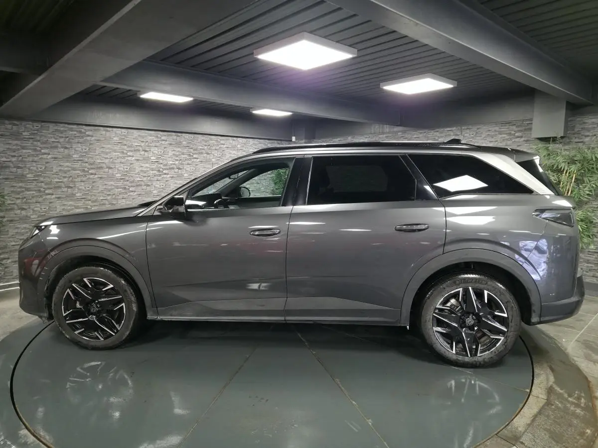 Peugeot 5008 gris métallisé vue de profil côté gauche, avec jantes alliage 19'' noires et barres de toit.