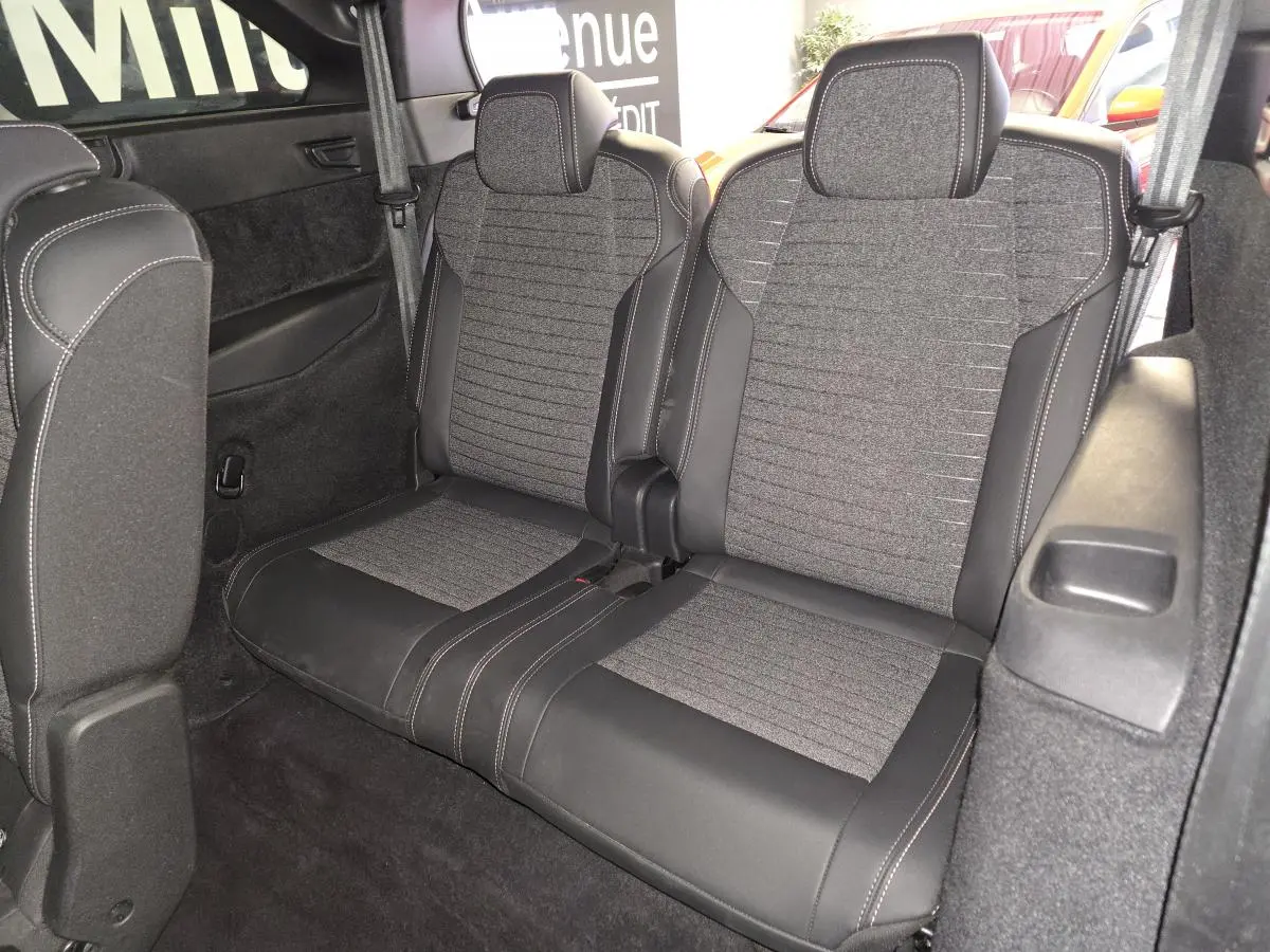 Vue intérieure des sièges arrière 3e rangée en tissu gris et cuir noir du Peugeot 5008 2025 hybride.