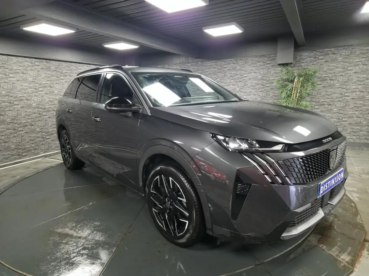 Peugeot 5008 gris métallisé vue 3/4 avant droit avec jantes alliage noires et calandre distinctive.