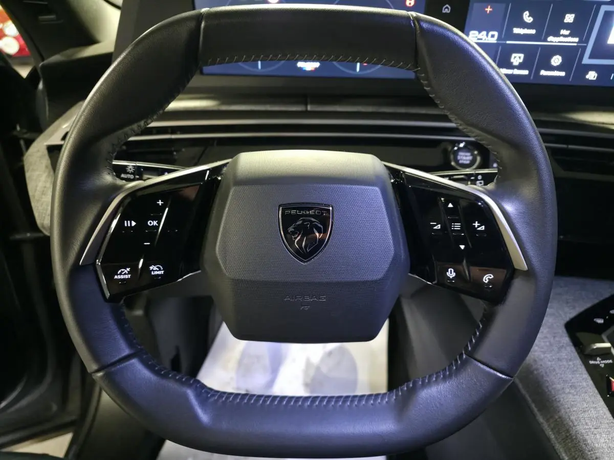 Vue rapprochée du volant noir de la Peugeot 5008 2025 avec commandes intégrées et logo lion central.