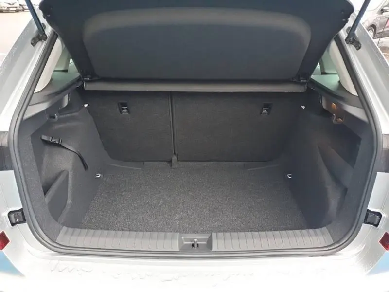 Coffre ouvert vu de l'arrière d'un Skoda Kamiq gris diamant métallisé, montrant l'espace de chargement vide.