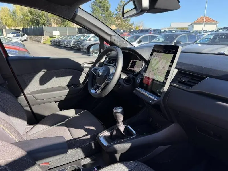 Vue intérieure côté conducteur du Renault Captur 2025 avec volant, écran tactile vertical et levier de vitesses manuel.