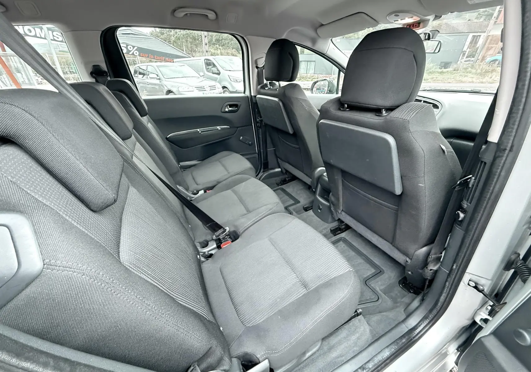 Vue intérieure côté droit montrant les sièges arrière en tissu gris du Peugeot 5008 gris de 2010 avec porte ouverte.