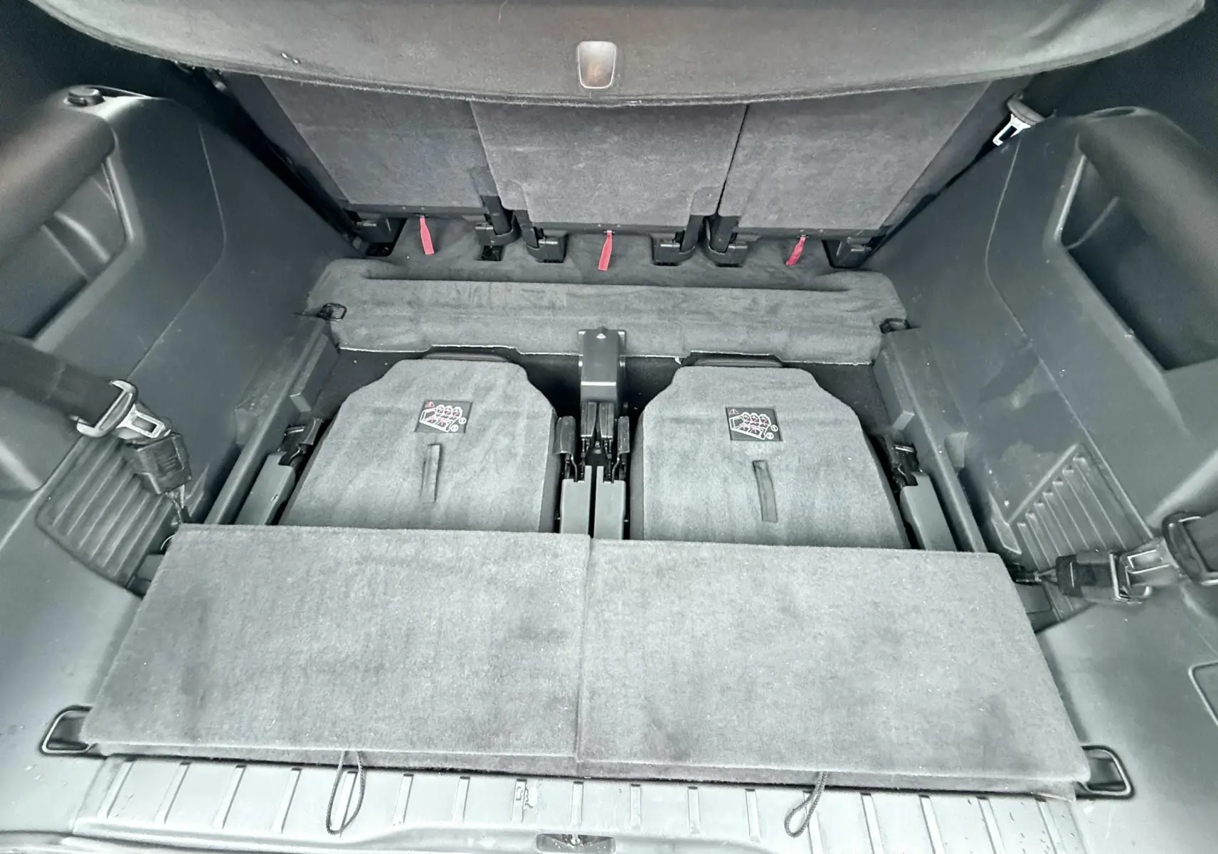Vue plongeante sur le coffre arrière du Peugeot 5008 gris, montrant les sièges arrière rabattus et l'espace de chargement.