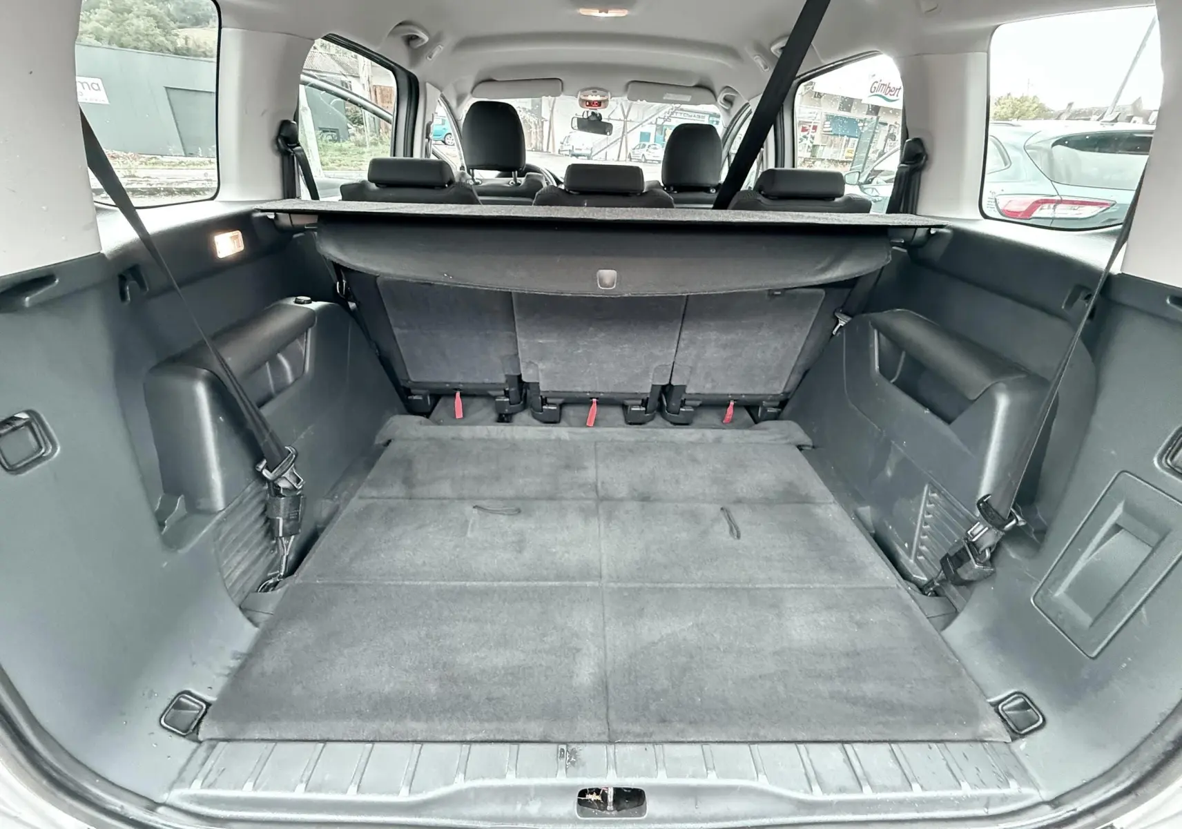Vue de l’intérieur du coffre spacieux d’un Peugeot 5008 gris avec banquette arrière rabattue et habillage noir.