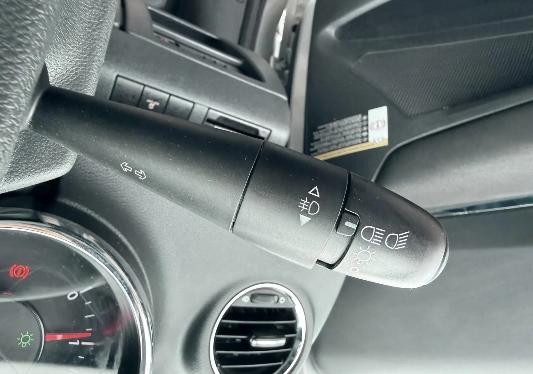 Gros plan sur la commande des phares et clignotants à gauche du volant dans l’habitacle gris d’un Peugeot 5008.