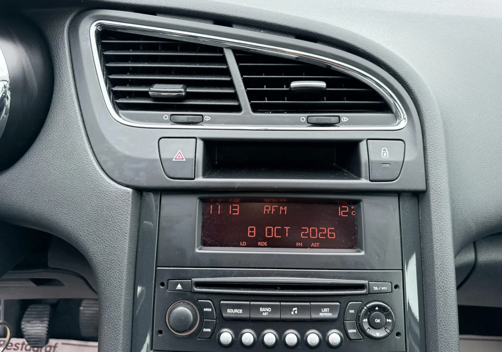 Vue rapprochée du tableau de bord gris du Peugeot 5008 avec affichage digital rouge et commandes radio.