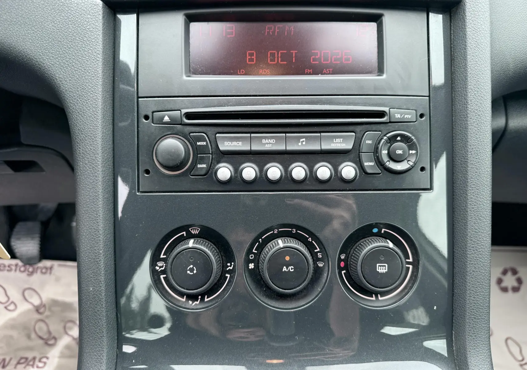 Vue rapprochée de la console centrale noire du Peugeot 5008 2010 montrant l’autoradio et les commandes de climatisation.
