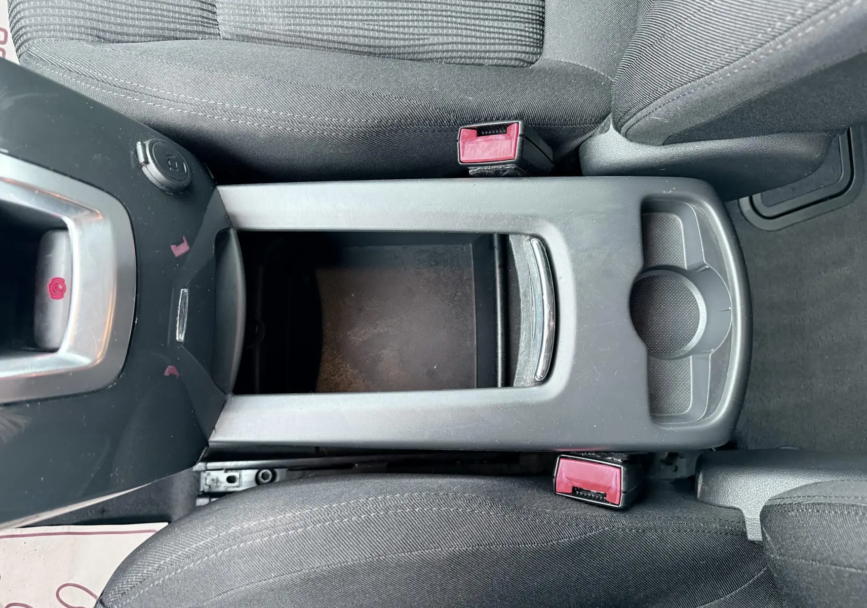 Vue plongeante sur la console centrale noire et les sièges tissu gris du Peugeot 5008 de 2010.