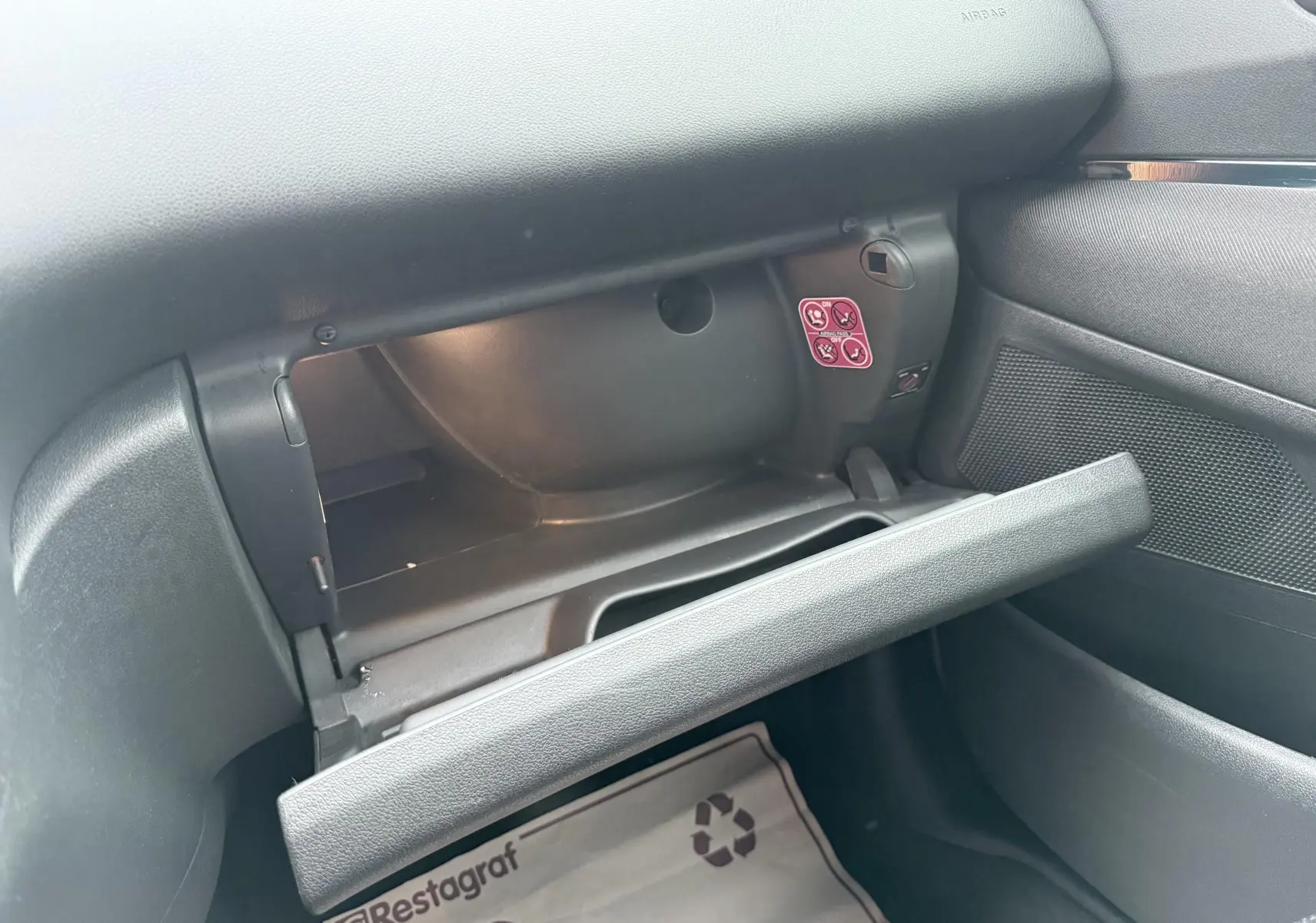 Vue intérieure du coffre à gants ouvert côté passager d'un Peugeot 5008 gris, montrant le tableau de bord et la porte du rangement.