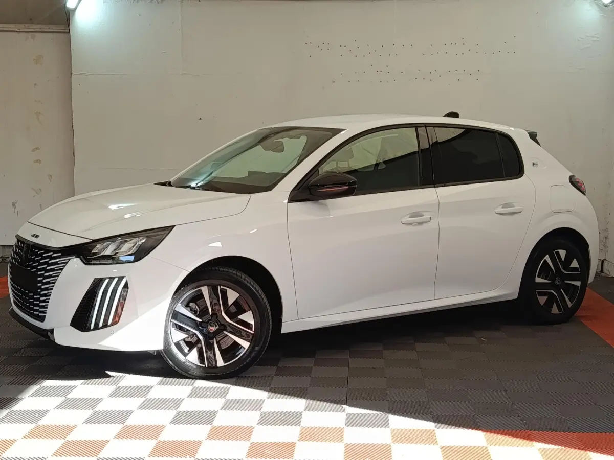 Peugeot 208 électrique blanche vue de profil côté gauche, avec jantes distinctives et feux LED avant.