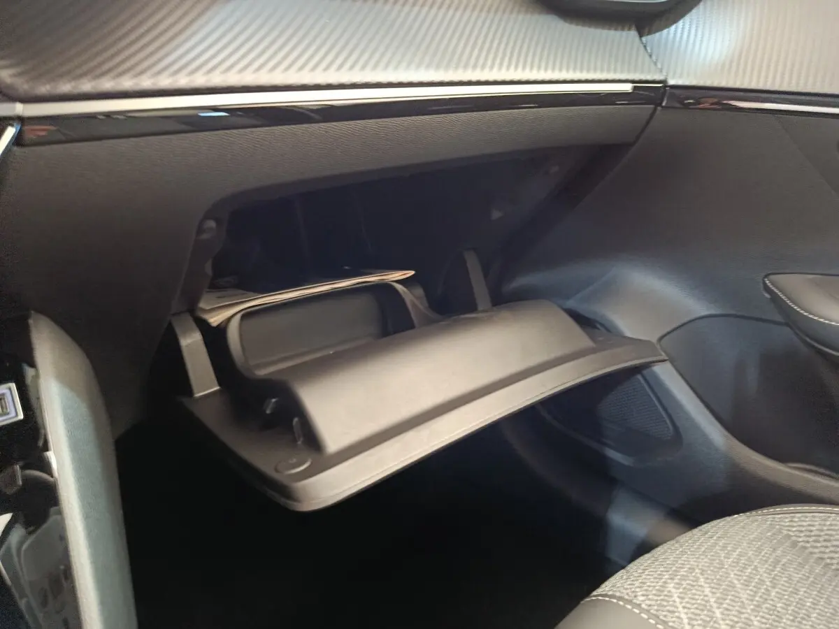 Vue intérieure du coffre à gants ouvert côté passager de la Peugeot 208 électrique blanche, montrant le rangement réfrigéré.