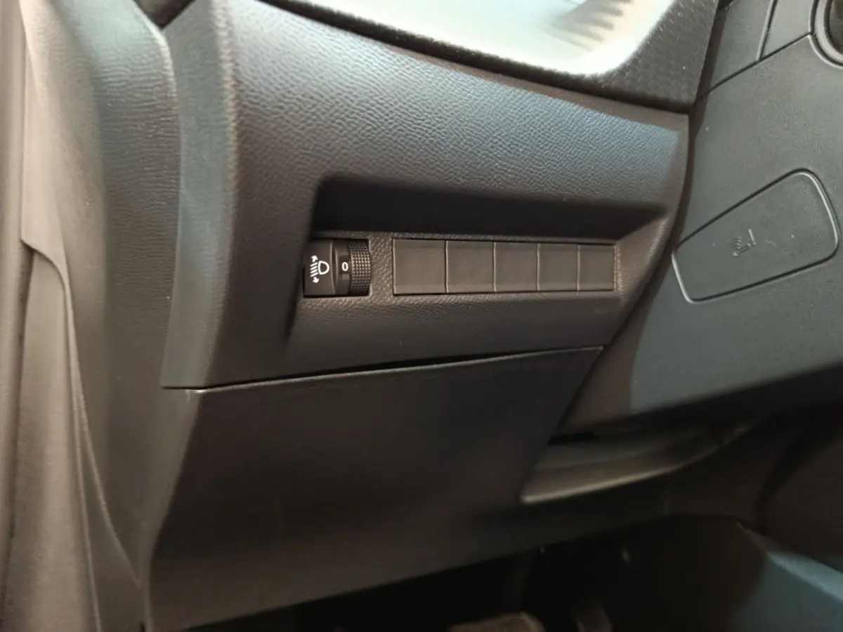 Détail intérieur côté conducteur du tableau de bord noir de la Peugeot 208 électrique blanche 2024.